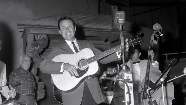Jim Reeves on the Grand Ole Opry, September 3, 1960 . Classic photo: Reeves is smiling, resting weight on left leg, and extends other foot so it looks as though he's walking. Gray-haired man in window-pane shirt is Opry stage manager and WSM libraria